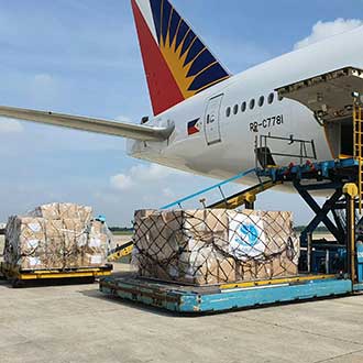 Beladener Frachtpalette vor Flugzeug – Symbol für internationale Luftfracht und Logistik.