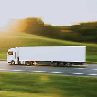 Lkw fährt über eine Landstraße – Symbol für effiziente Transport- und Logistiklösungen.