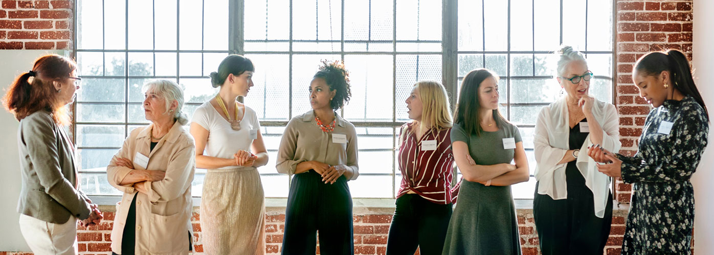 Gruppe von Frauen im Gespräch bei einer Veranstaltung – Symbol für Austausch und Vernetzung im Qualitätsmanagement.
